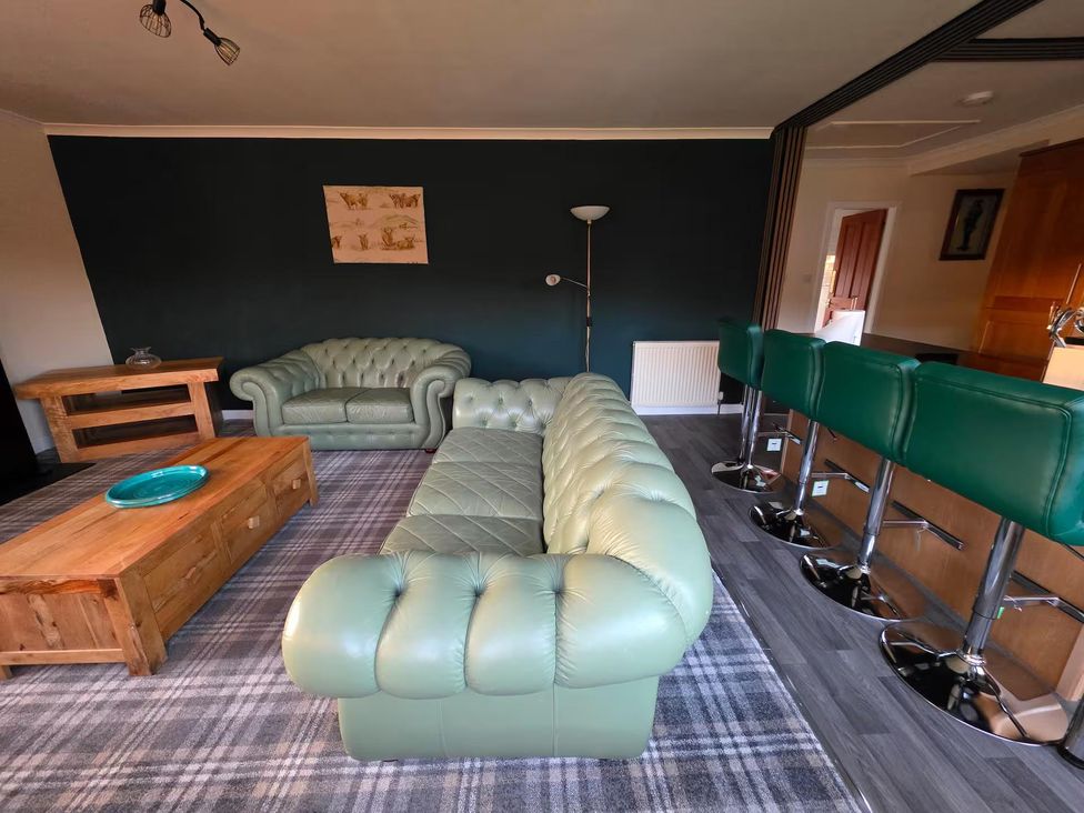 A living room with a green sofa and wooden coffee table at Highlands - River View - Apt - Sleeps 4 - Garden, Garve near Strathpeffer