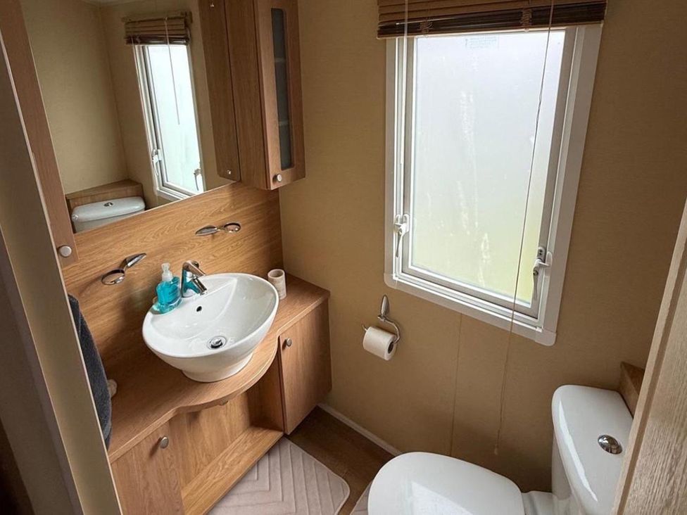 A bathroom with sink, toilet, and window at 2-Bed Caravan, Sleeps 6 w/ Parking, No Pass Needed