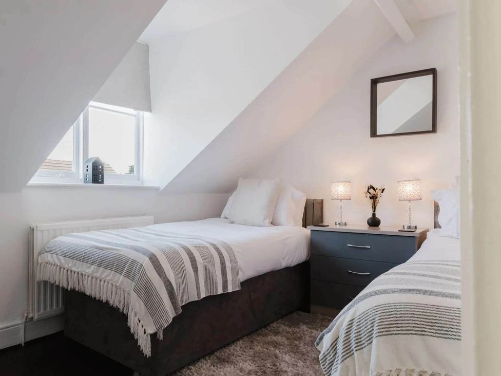 A bedroom with two beds and a nightstand at Licatas Apartment Cirencester Cotswolds Sleeps 6