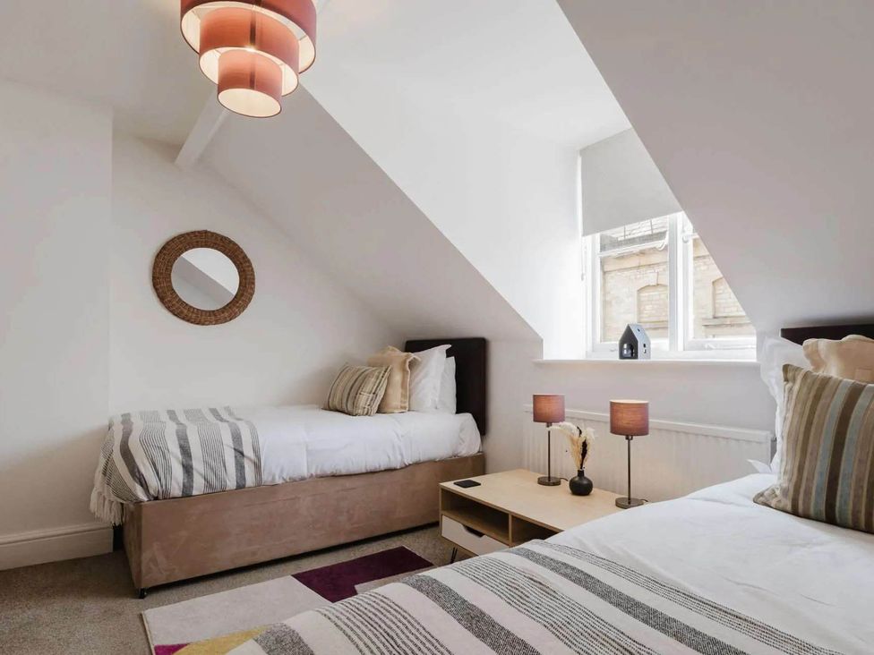 A bedroom with two beds and a side table at Licatas Apartment Cirencester Cotswolds Sleeps 6