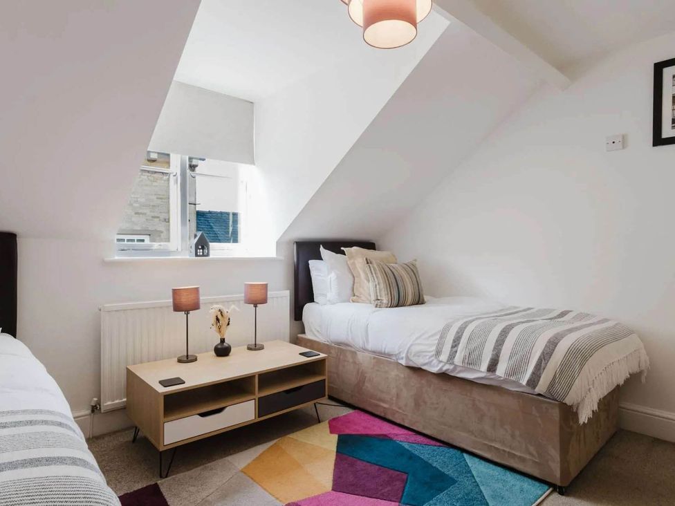 A bedroom with beds and a coffee table at Licatas Apartment Cirencester Cotswolds Sleeps 6