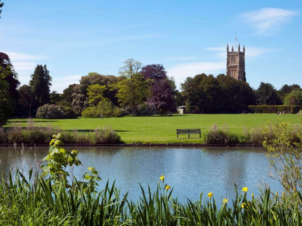 A view of a park with a river and a tower at Licatas Apartment Cirencester Cotswolds Sleeps 6