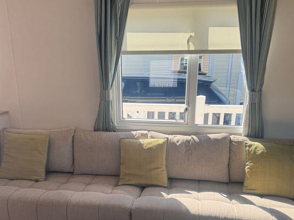 A living room with a couch and window at Caravan - Sleeps 6 - Parking in Lossiemouth