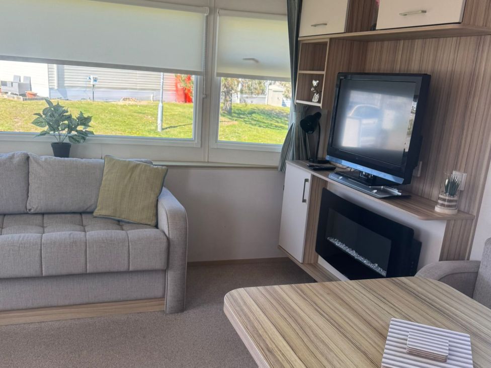 A living room with a sofa and television at Caravan - Sleeps 6 - Parking in Lossiemouth