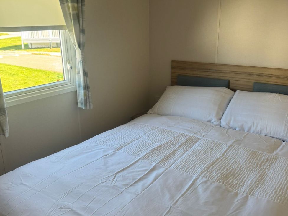 A bedroom with a bed and window at Caravan - Sleeps 6 - Parking in Lossiemouth