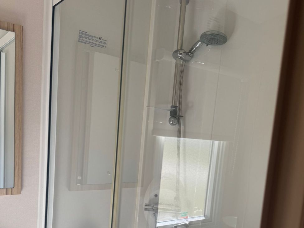 A shower with a showerhead and a mirror at Caravan - Sleeps 6 - Parking Lossiemouth