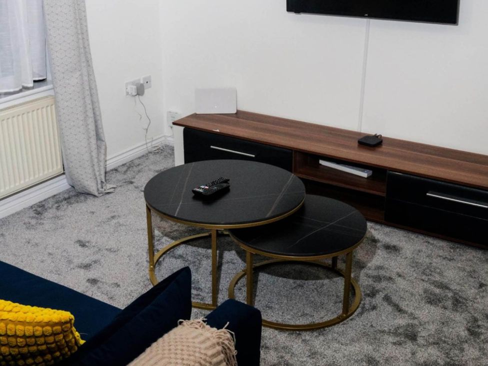 A living room featuring a coffee table with a remote and television at House Sleeps 5 with Garden and Parking