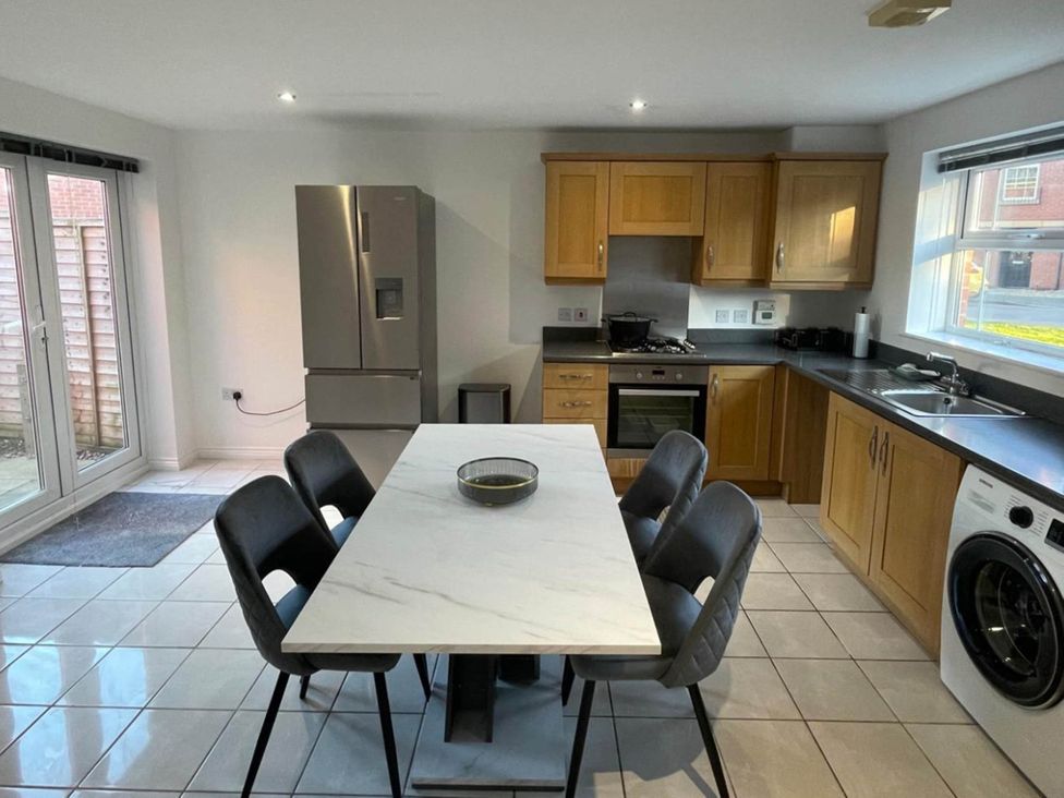 A kitchen with a dining table and appliances at House Sleeps 5 with Garden and Parking