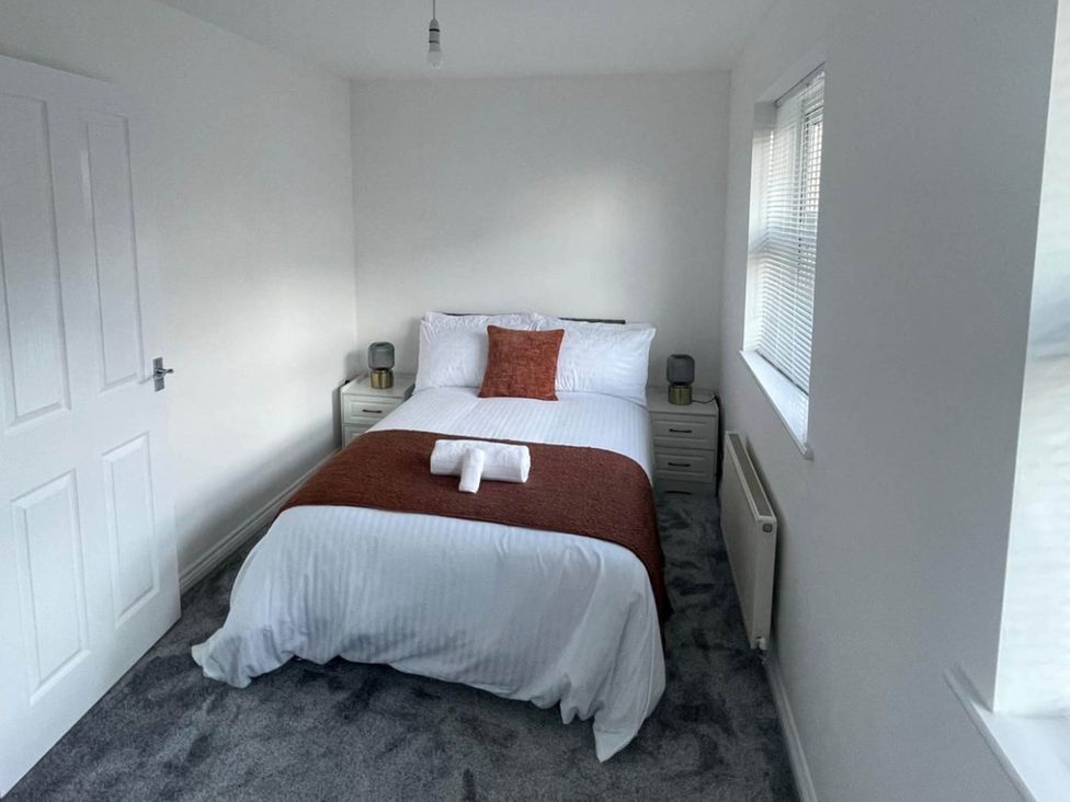 A bedroom with a bed and nightstand at House Sleeps 5 with Garden and Parking
