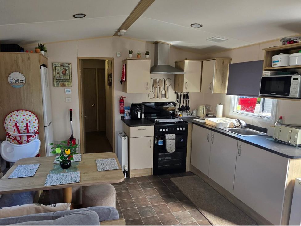 A kitchen with appliances and seating at D&T Caravan Hire Southview Holiday Park Skegness