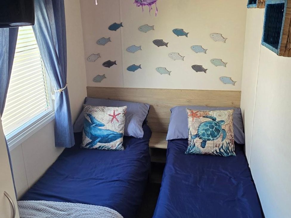 A bedroom with two beds and fish decorations at D&T Caravan Hire Southview Holiday Park Skegness