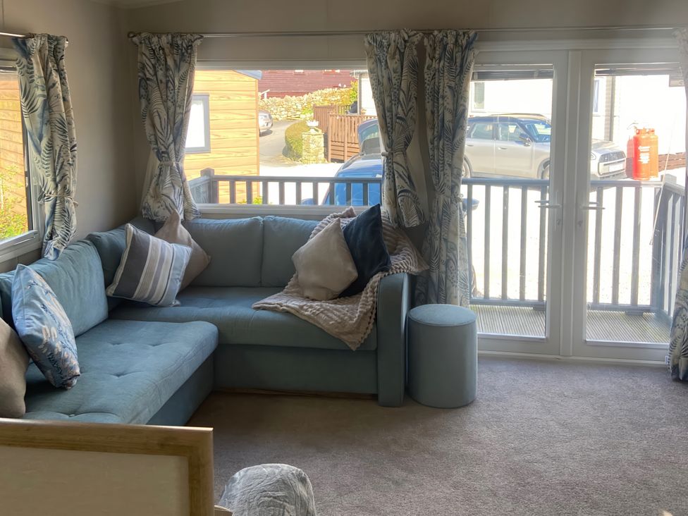 A living room with a sofa and cushions at Coworth Deluxe Cabin with Garden