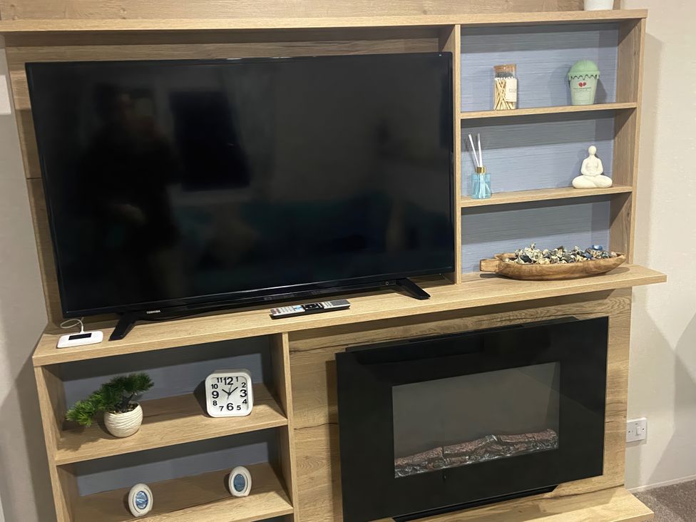 A living room with television and decorative items at Coworth Deluxe Cabin with Garden