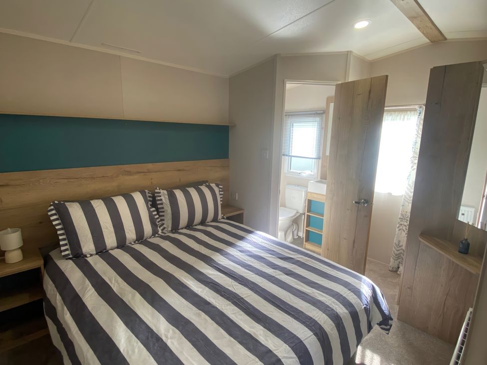 A bedroom with a bed and adjoining bathroom at Coworth Deluxe Cabin with Garden