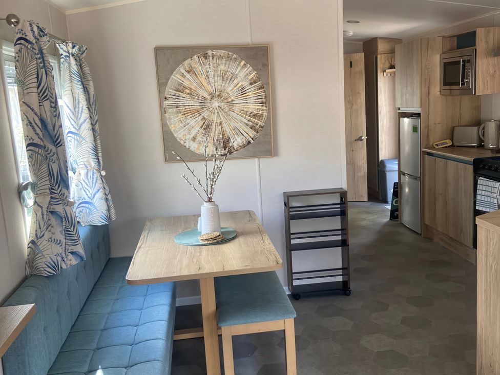 A dining area with table and kitchen appliances at Coworth Deluxe Cabin with Garden