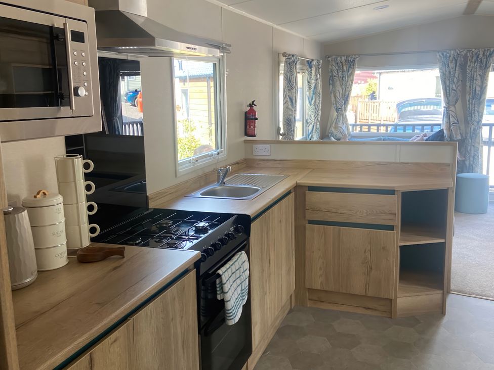 A kitchen with stove and sink at Coworth Deluxe Cabin with Garden
