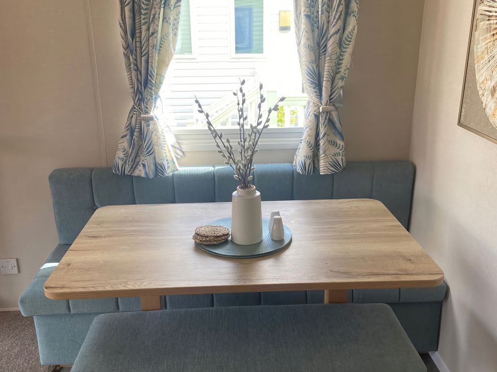 A dining area with a table and bench seating at Coworth Deluxe Cabin with Garden
