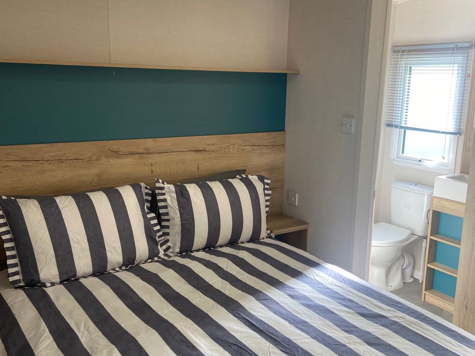 A bedroom with a bed and a toilet in the corner at Coworth Deluxe Cabin with Garden