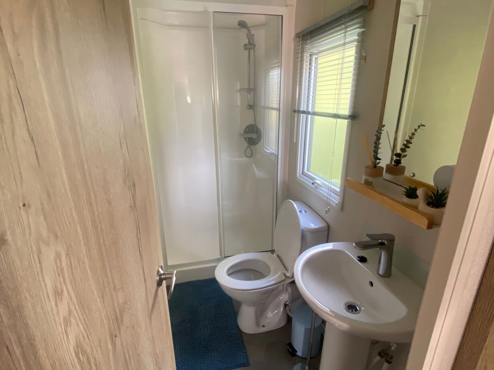 A bathroom with a shower, toilet, and sink at Coworth Deluxe Cabin with Garden