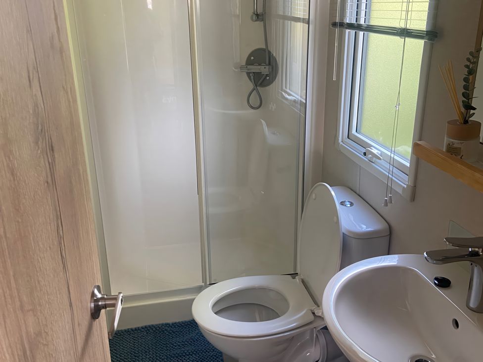 A bathroom with shower, toilet, and sink at Coworth Deluxe Cabin with Garden