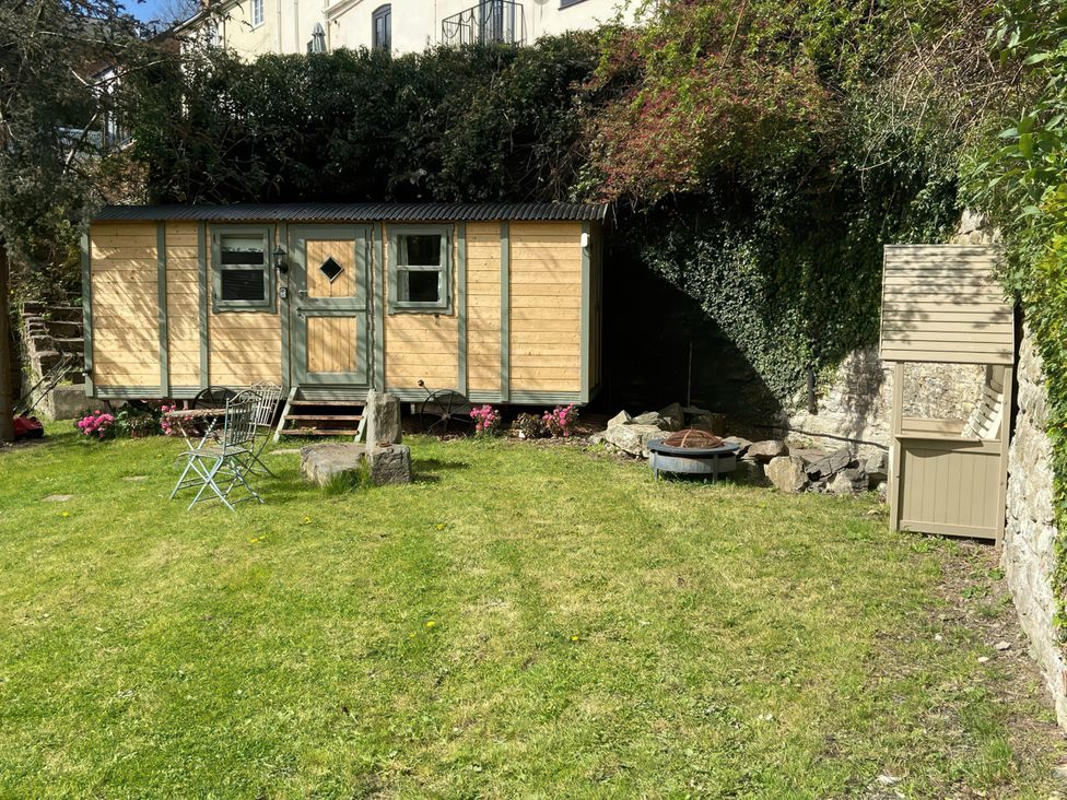 A garden with a wooden shed and fire pit at Cozy Cabin Retreat in Newtown