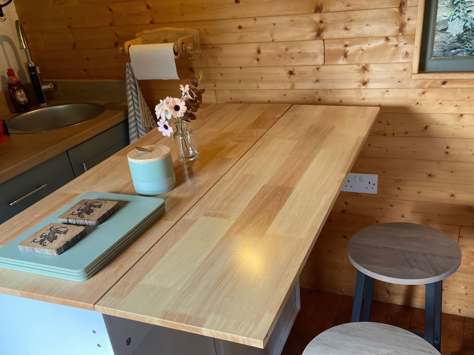 A kitchen with a wooden table and stools at Cozy Cabin Retreat in Newtown