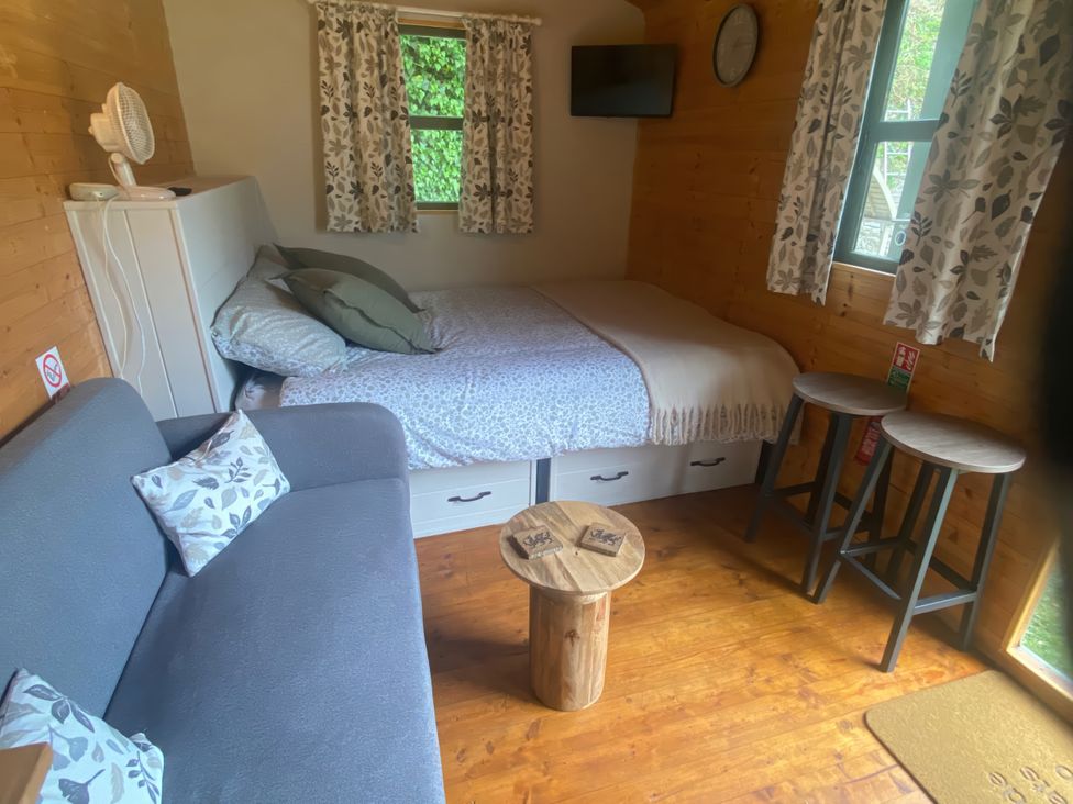 A bedroom with a bed, couch, and table at Cozy Cabin Retreat in Newtown