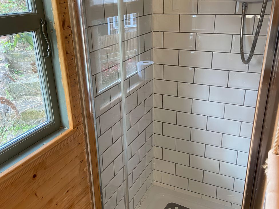 A shower with glass door and tiled wall at Cozy Cabin Retreat in Newtown