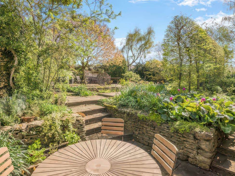 A garden with a wooden table and chairs at Cotswolds - Garden - Bbq - Parking - Sleeps 6 near Shipston-On-Stour