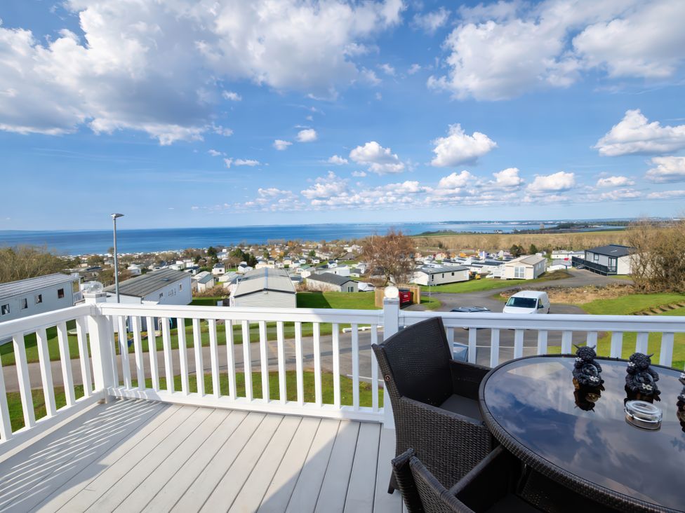 A deck with a table and chairs overlooking the sea at Caravan Sleeps 6 with Sea Views and Parking in Ayr