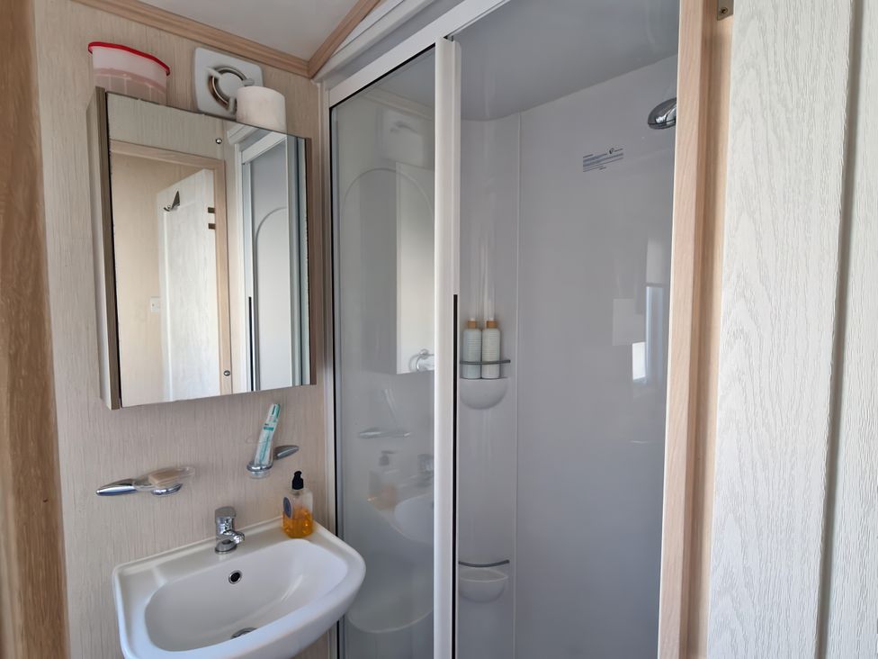 A bathroom with a sink and shower at Caravan Sleeps 6 with Sea Views and Parking located in Ayr