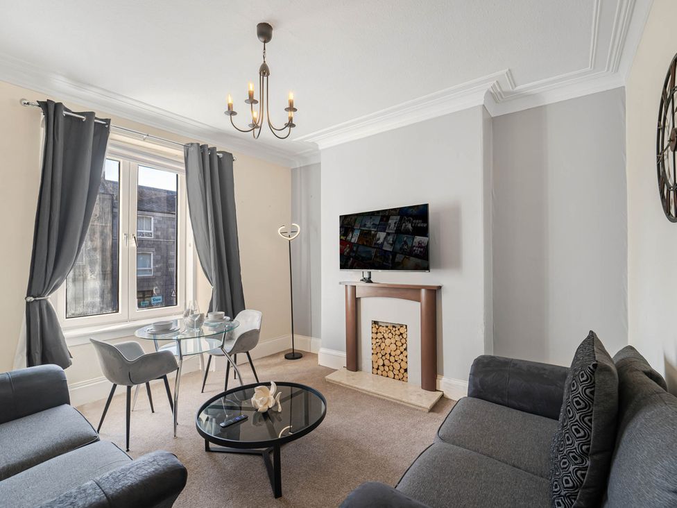 A living room with a sofa, coffee table, and television at Central Aberdeen flat Holburn St workspace parking in Aberdeen
