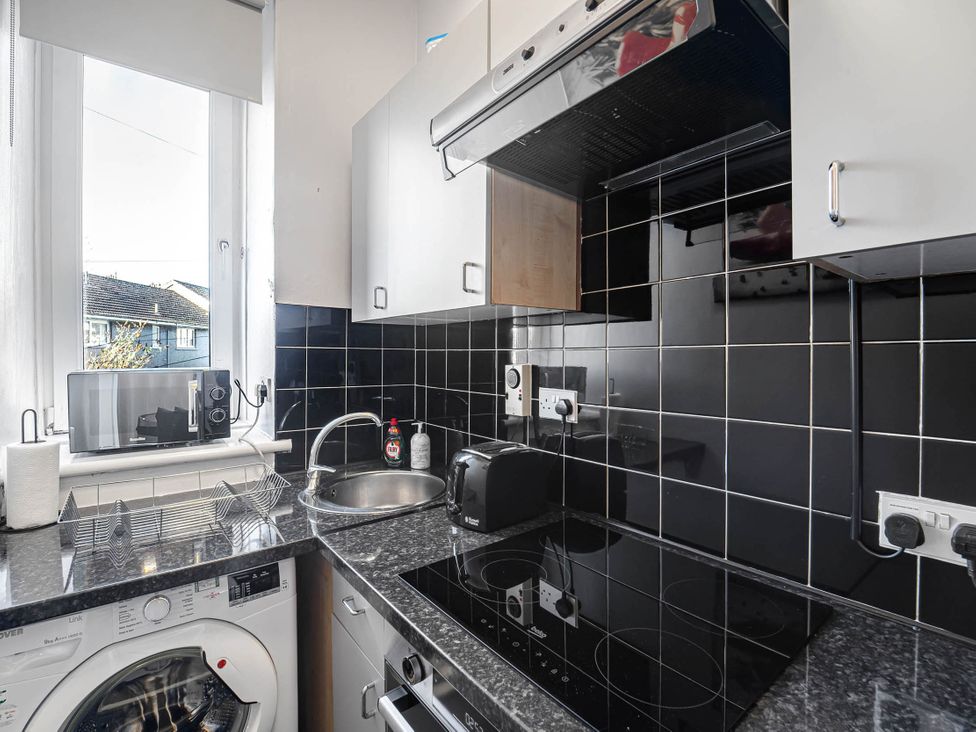 A kitchen with a sink, microwave, and washing machine at Central Aberdeen flat Holburn St workspace parking, Aberdeen