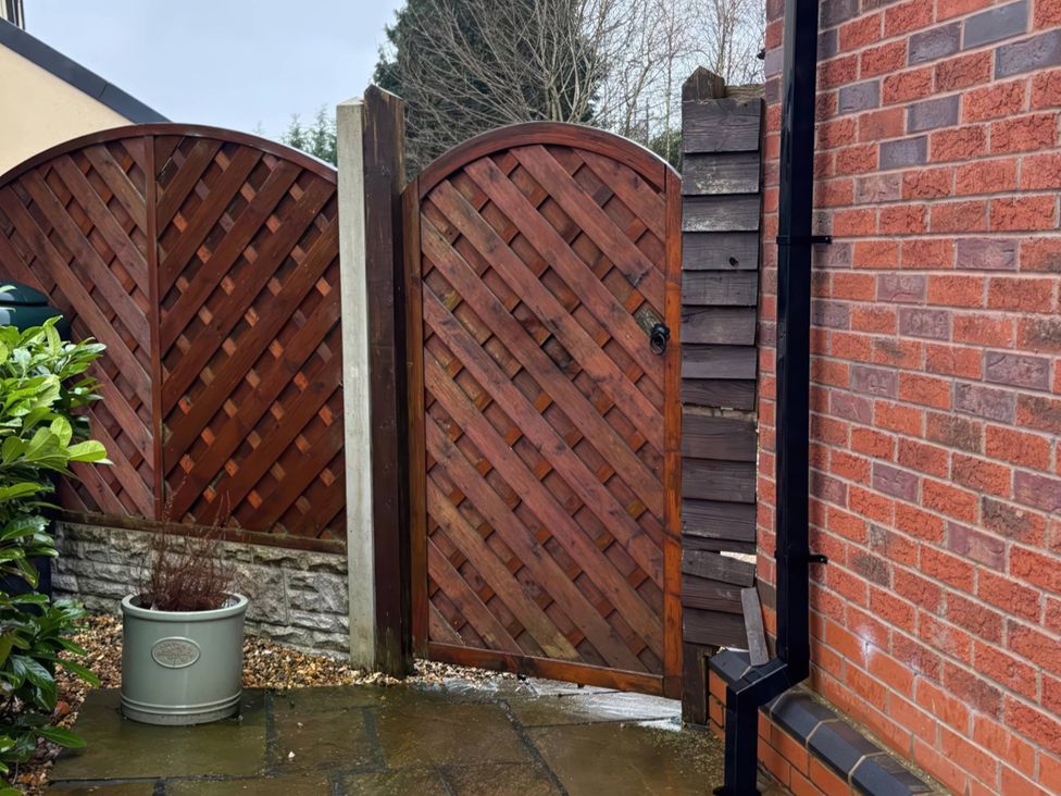 A wooden gate next to a wooden fence and brick wall with a plant pot at Rural 2 double bedrooms Barn Mill Meece near Eccleshall