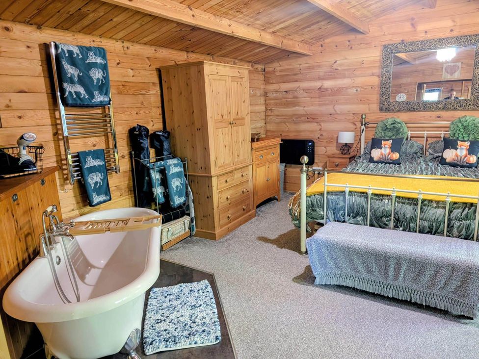 A bedroom with a bathtub and a bed at Forest Cabin Retreat-Sleeps 2-Garden, Wifi, Trails in Alderholt