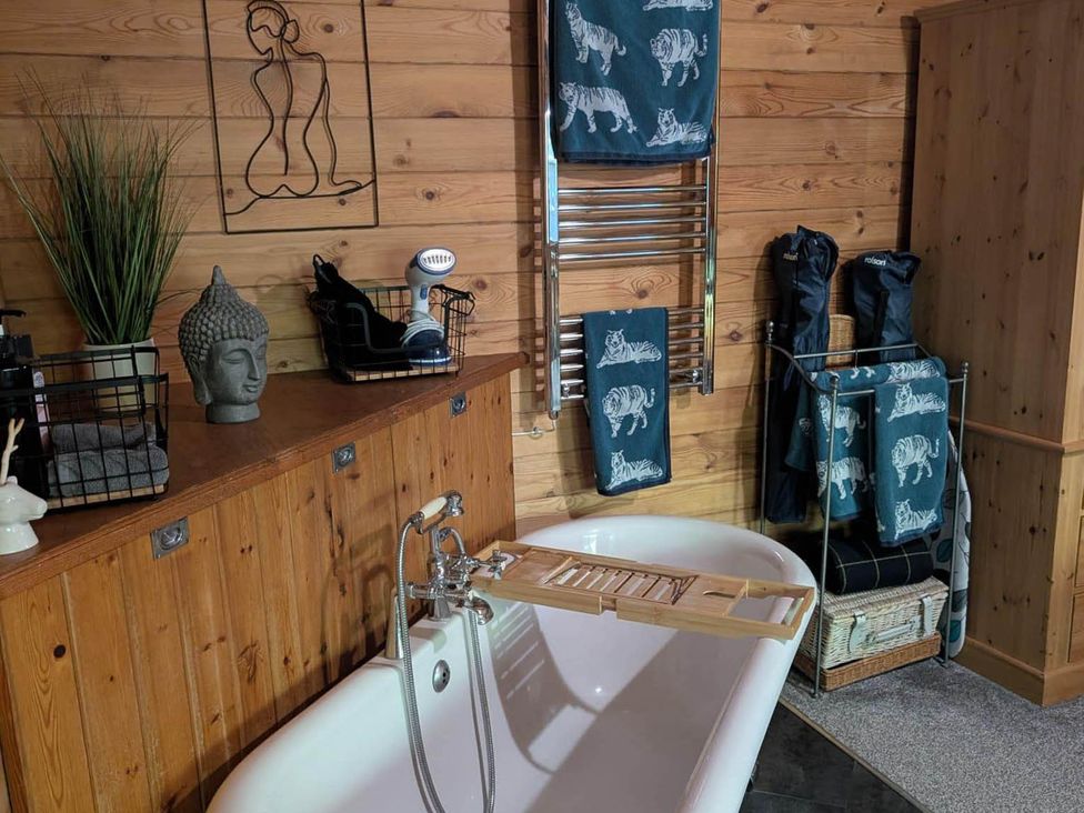 A bathroom with a bathtub and towels at Forest Cabin Retreat-Sleeps 2-Garden, Wifi, Trails, Alderholt