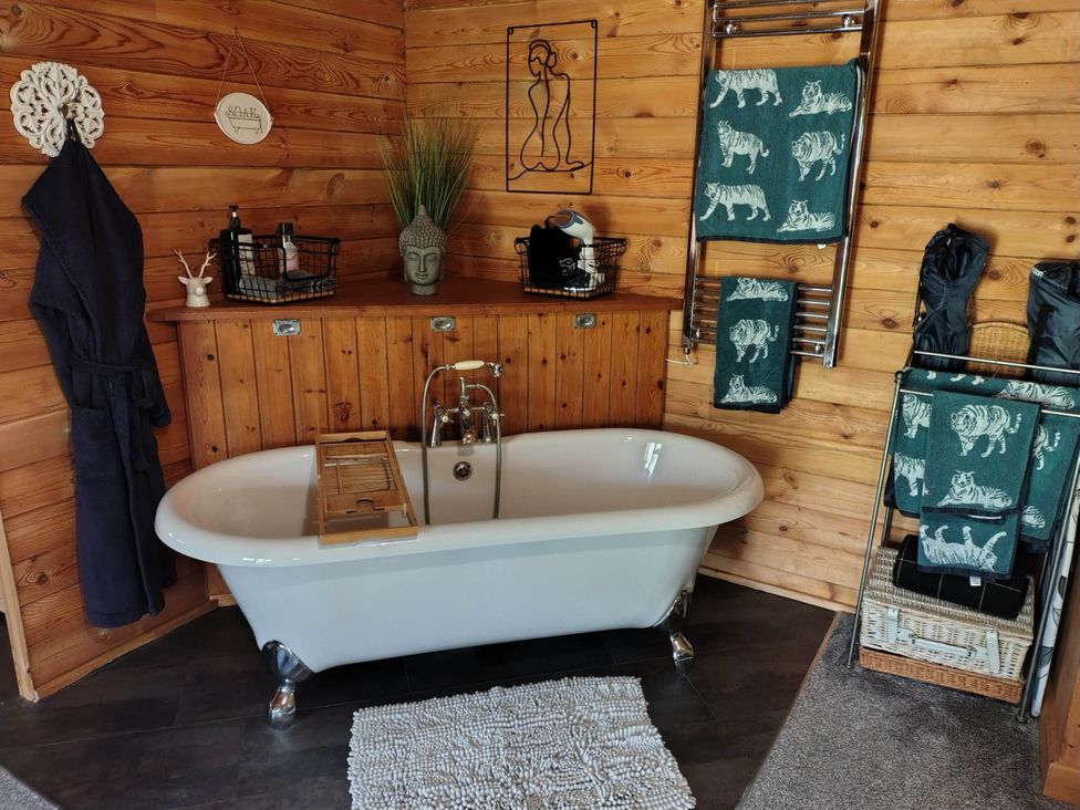 A bathroom with a bathtub and towel rack at Forest Cabin Retreat-Sleeps 2-Garden, Wifi, Trails, Alderholt