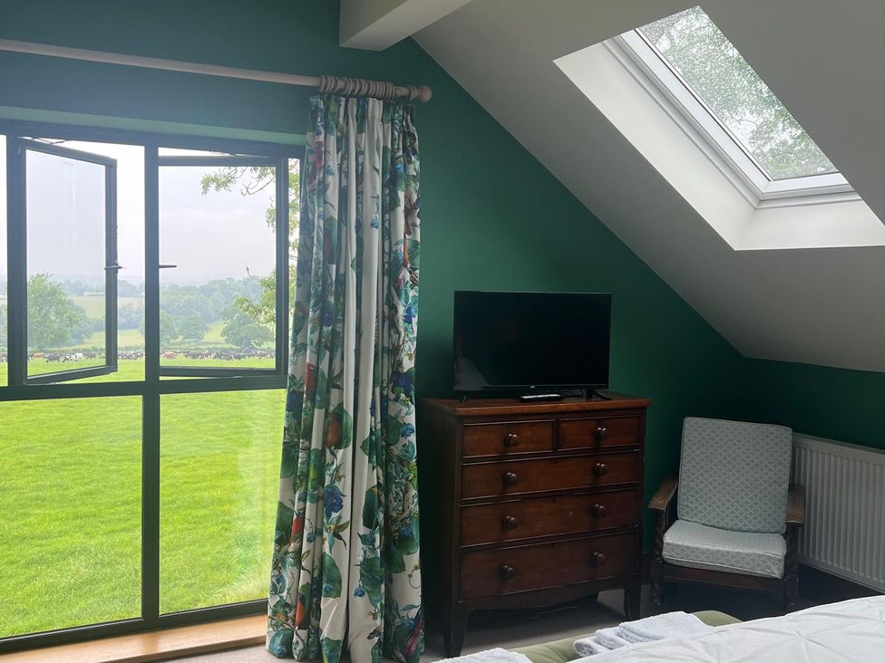 A bedroom with a window, curtains, television, and armchair at 2 Guests Studio - Free Parking - Stunning Views near Bruton
