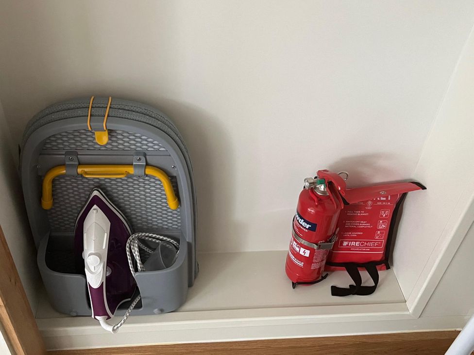 A utility room with an ironing board and fire safety equipment at 2 Guests Studio - Free Parking - Stunning Views near Bruton