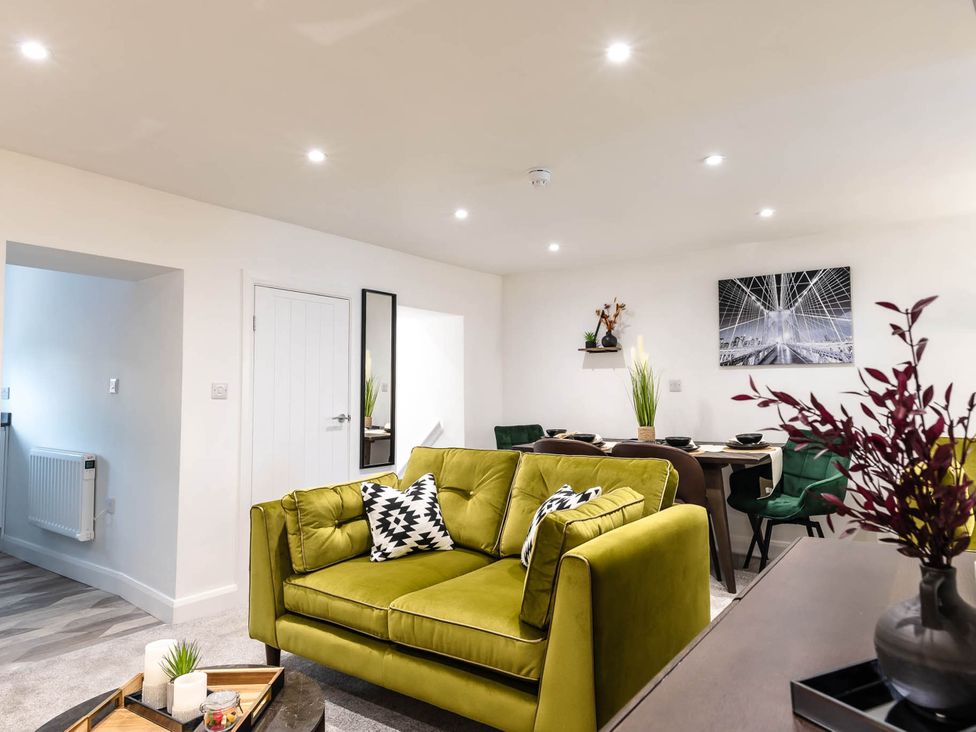 A living room with a green sofa and dining area at Cosy 2-Bed Apartment in Nettleham
