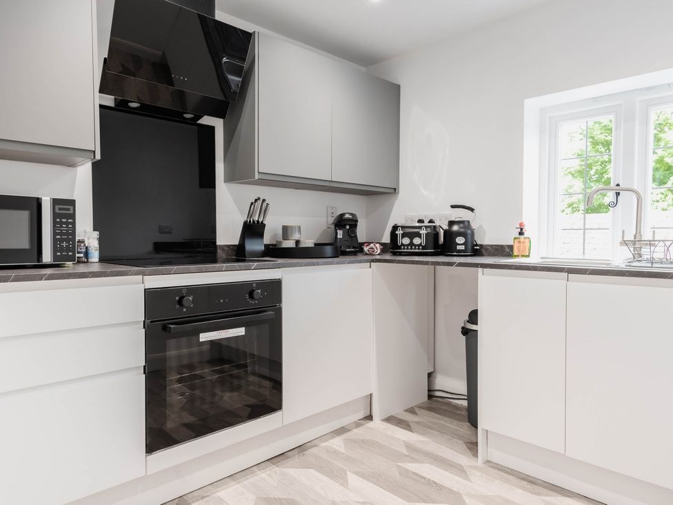 A kitchen with cabinets and appliances at Cosy 2-Bed Apartment in Nettleham