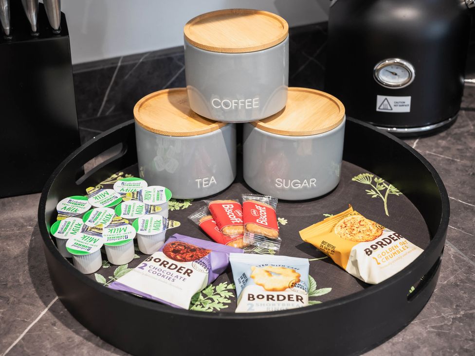 A kitchen tray with coffee, tea, sugar canisters and snacks at Cosy 2-Bed Apartment in Nettleham