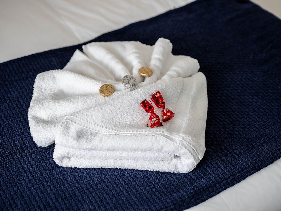 A display of towels with coins and candies on a bed at Cosy 2-Bed Apartment in Nettleham