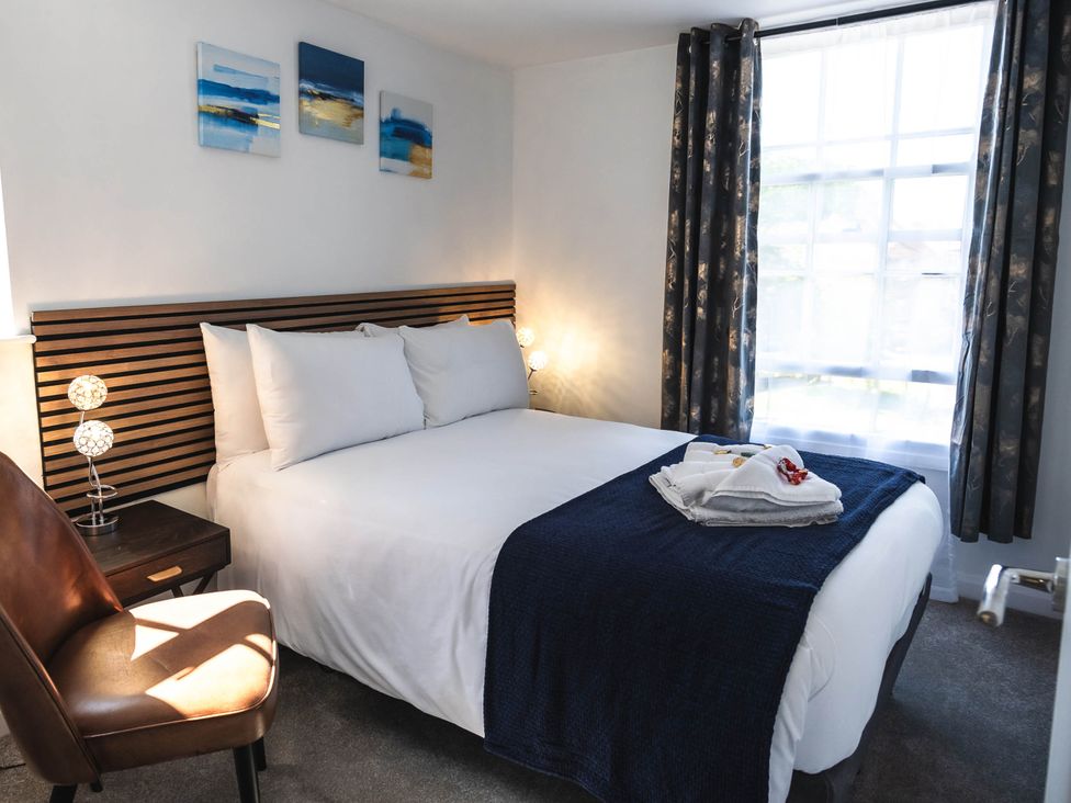 A bedroom with a bed and chair at Cosy 2-Bed Apartment in Nettleham