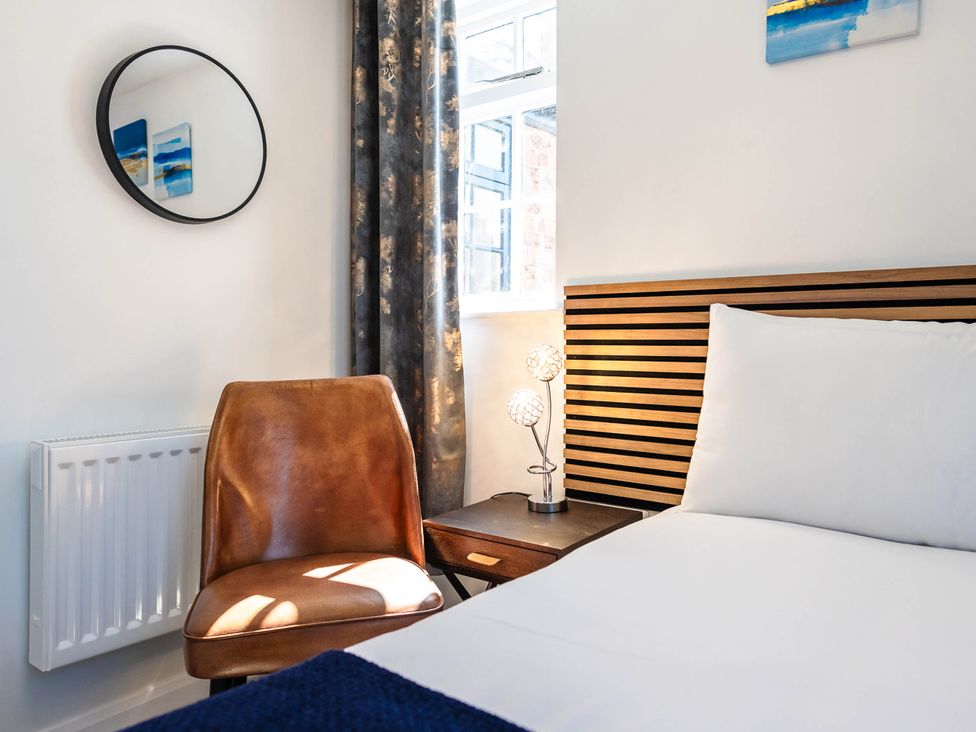 A bedroom with a bed and a chair at Cosy 2-Bed Apartment in Nettleham