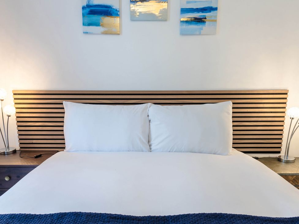 A bed with pillows and bedside lamps at Cosy 2-Bed Apartment in Nettleham