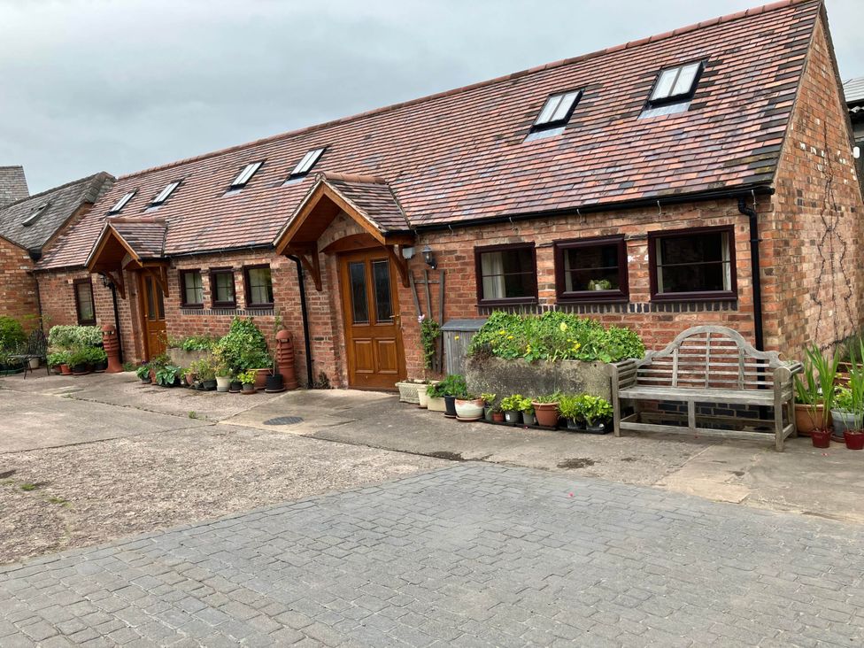 An outdoor view of a brick building with windows and flower pots at Cottage in Nuneaton - Sleeps 2 - Parking - Garden Higham-on-the-Hill near Nuneaton