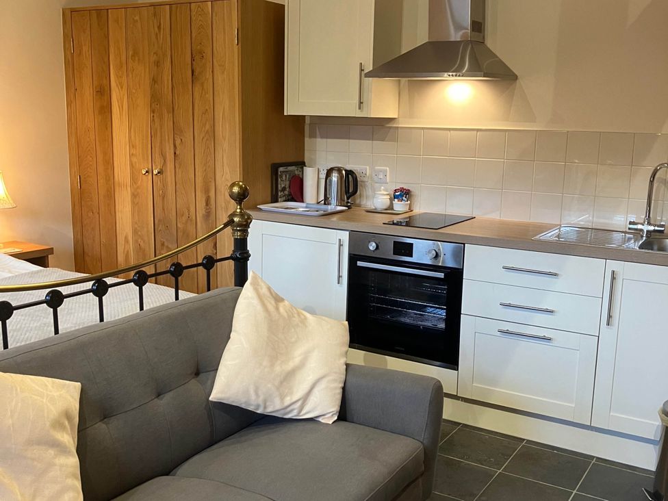 A studio with a kitchen area and sofa at Cottage in Nuneaton - Sleeps 2 - Parking - Garden Higham-on-the-Hill near Nuneaton