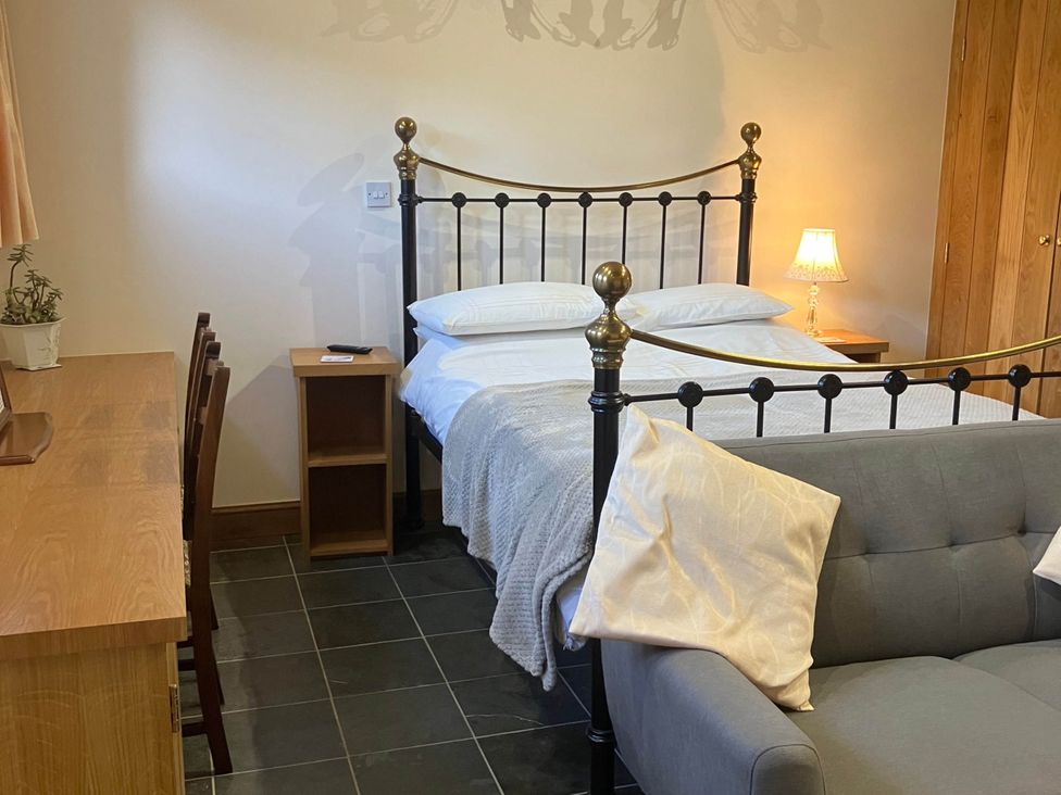 A bedroom with a bed, sofa, desk, and lamp at Cottage in Nuneaton - Sleeps 2 - Parking - Garden, Higham-on-the-Hill near Nuneaton