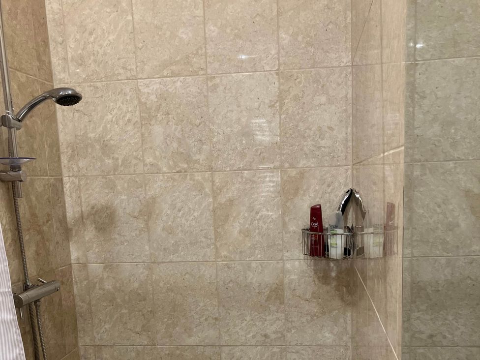 A shower with products in a shelf at Cottage in Nuneaton - Sleeps 2 - Parking - Garden, Higham-on-the-Hill near Nuneaton
